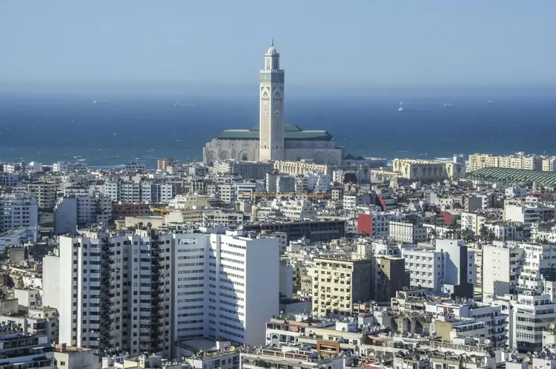 The Hassan II Mosque seen across Casablanca's rooftops with the sea behind